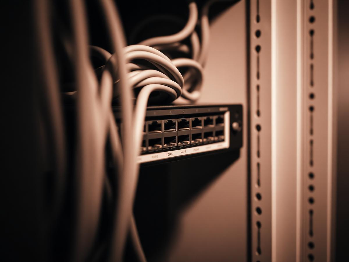 A neatly terminated network switch in a wall-mounted rack.